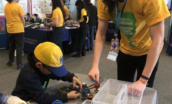 Photo shows child putting together a model at Edinburgh Science Festival with adult overseeing.