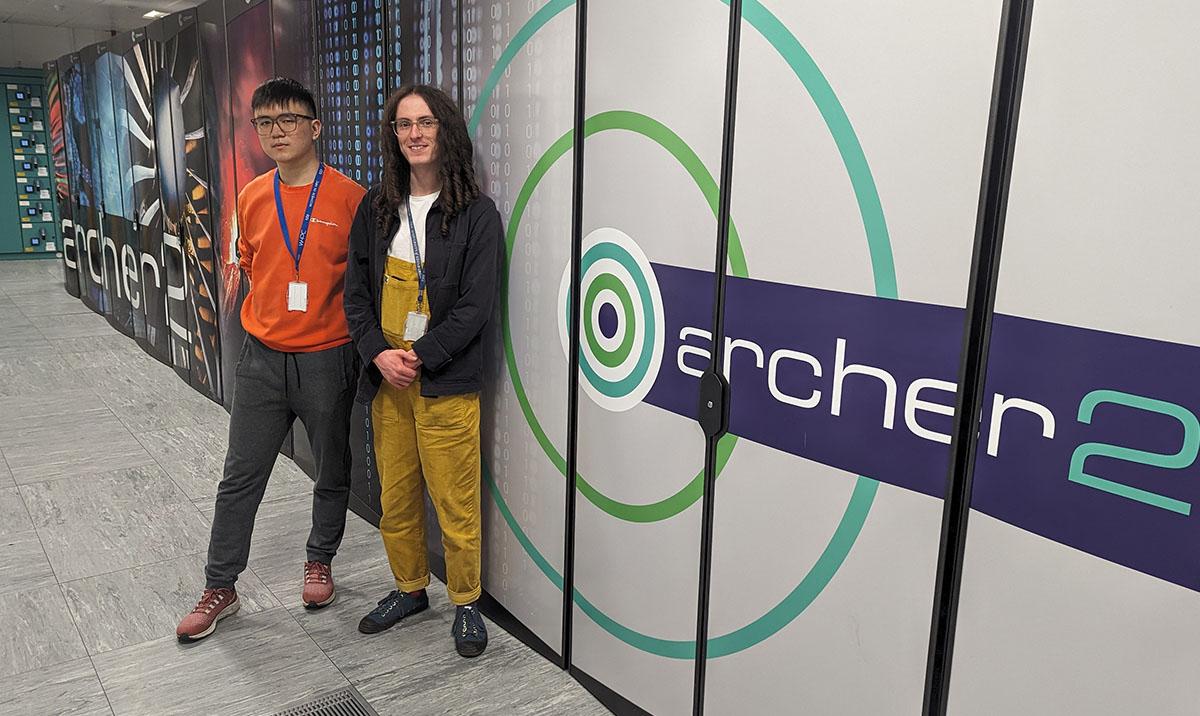 Photo shows two men standing in front of ARCHER2 supercomputer