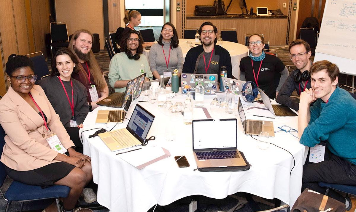 9 people seated around round table in workshop setting.