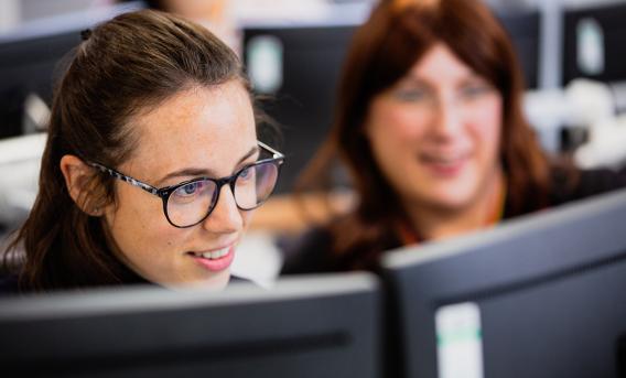 Two women looking at computer monitor in classroom setting